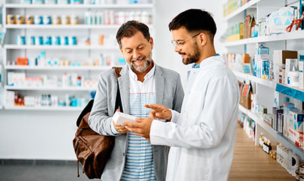 A pharmacist is handing over a prescription to a man.